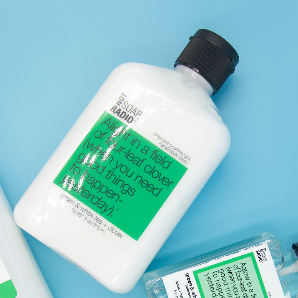An intensive positive luck hand and body lotion for women flatlay on a blue background.