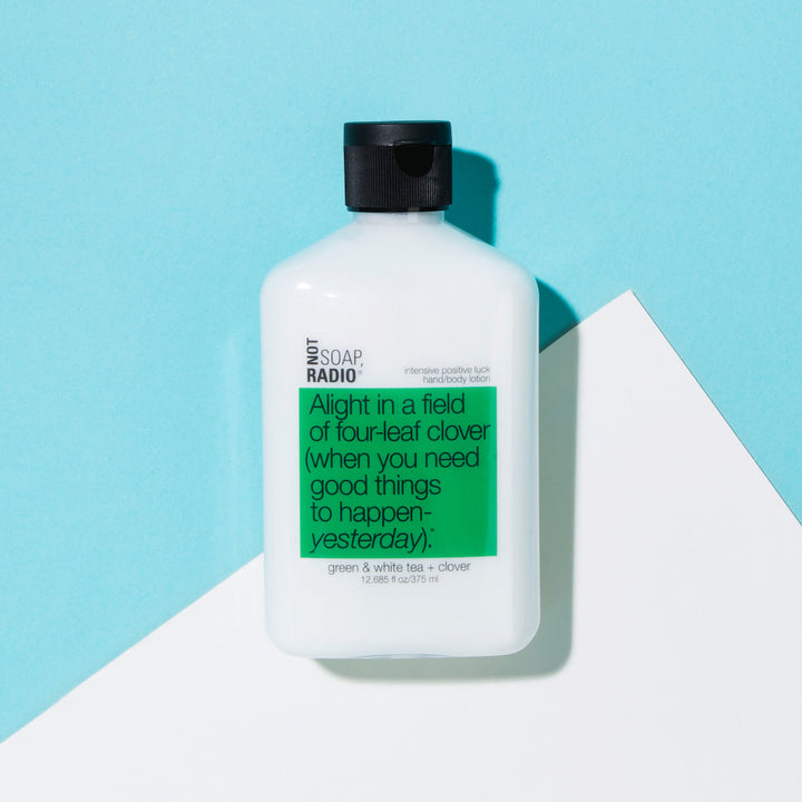 A Not Soap Radio hand and body lotion that is green tea and white tea scented laying on a blue and white background.