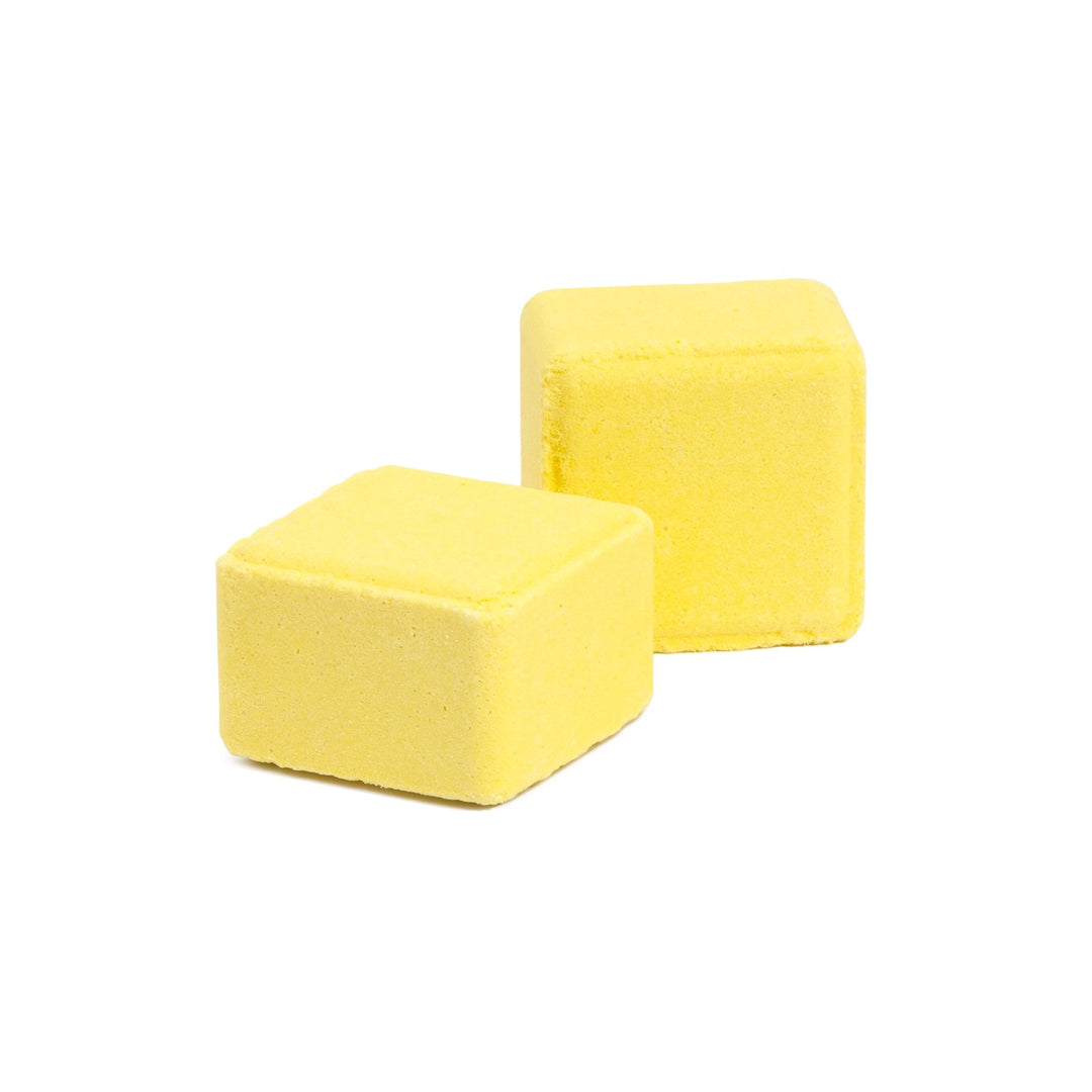 Close-up of 2 lemon + sugar scented shower steamer cubes, joy inducing lemon essential oil aromatherapy shower tablets