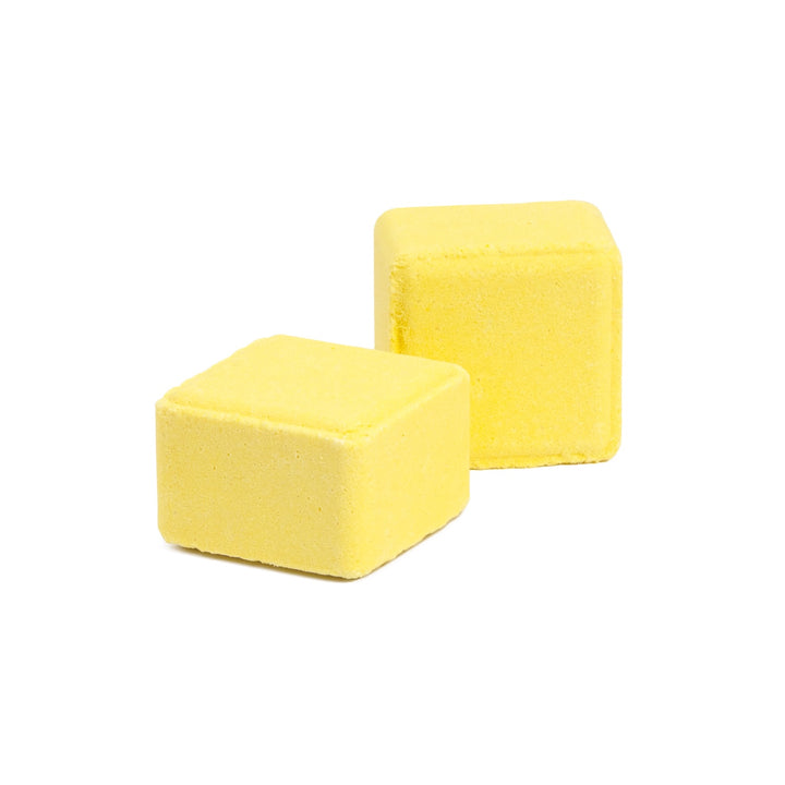 Close-up of 2 lemon + sugar scented shower steamer cubes, joy inducing lemon essential oil aromatherapy shower tablets