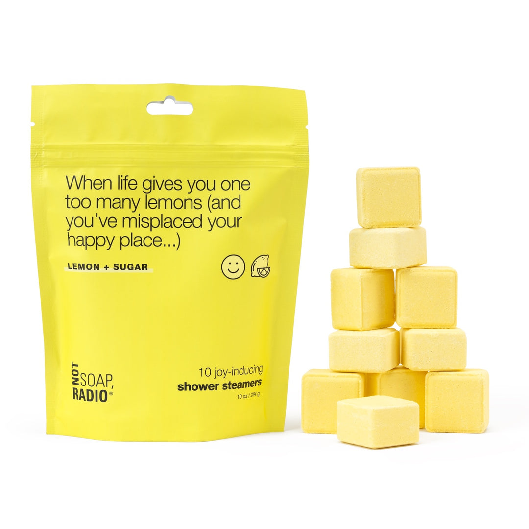 Lemon + sugar scented shower steamers in yellow pouch with title "When life gives you one too many lemons (and you've misplaced your happy place...)", 10-pack of aromatherapy shower steamers stacked in pyramid next to bag