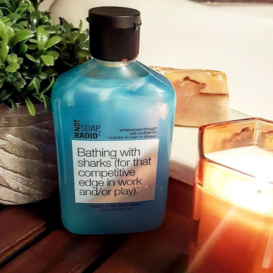 A lifestyle arrangement of the blue bubble bath next to a succulent and a candle.