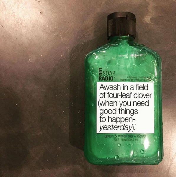 A positive reinforcement green shower or bubble bath gel laying on top of a shiny black background.