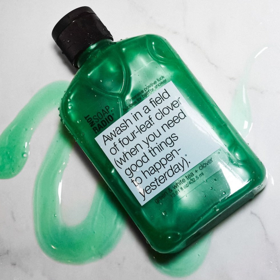 A 4 leaf clover extract bath and shower gel laying on top of a smear of the soap.
