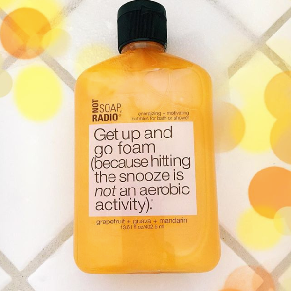 A green colored shower gel on top of a white tile background that has matching orange circles around it.