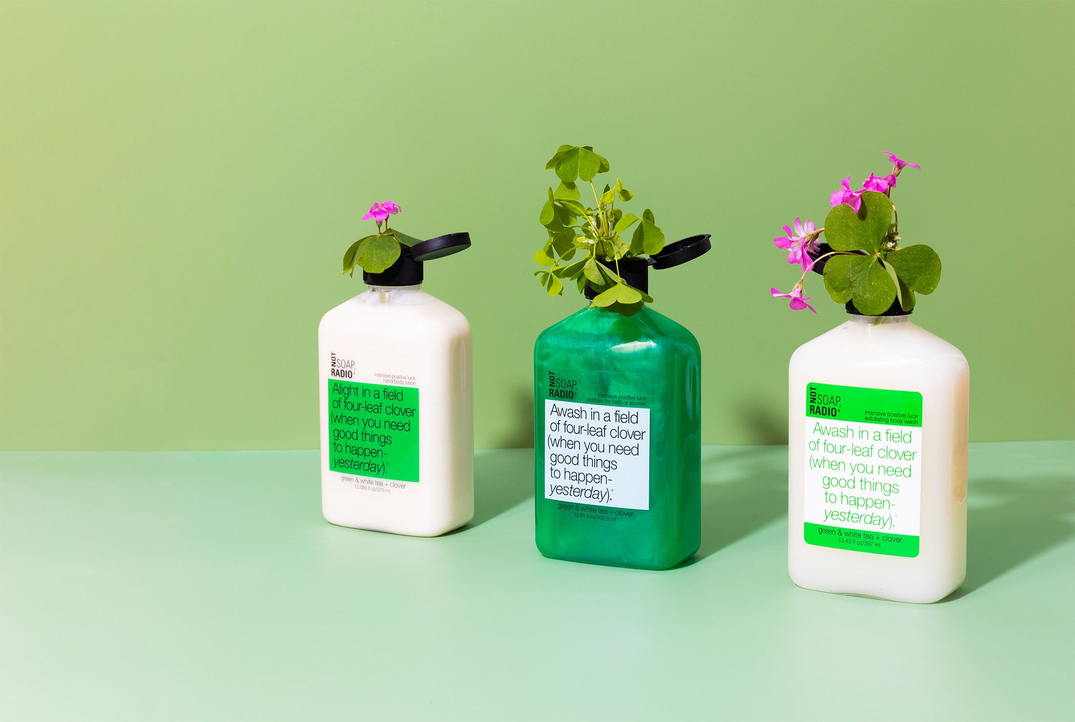 Green and white tea scented bath and body care products with clovers coming out of the top