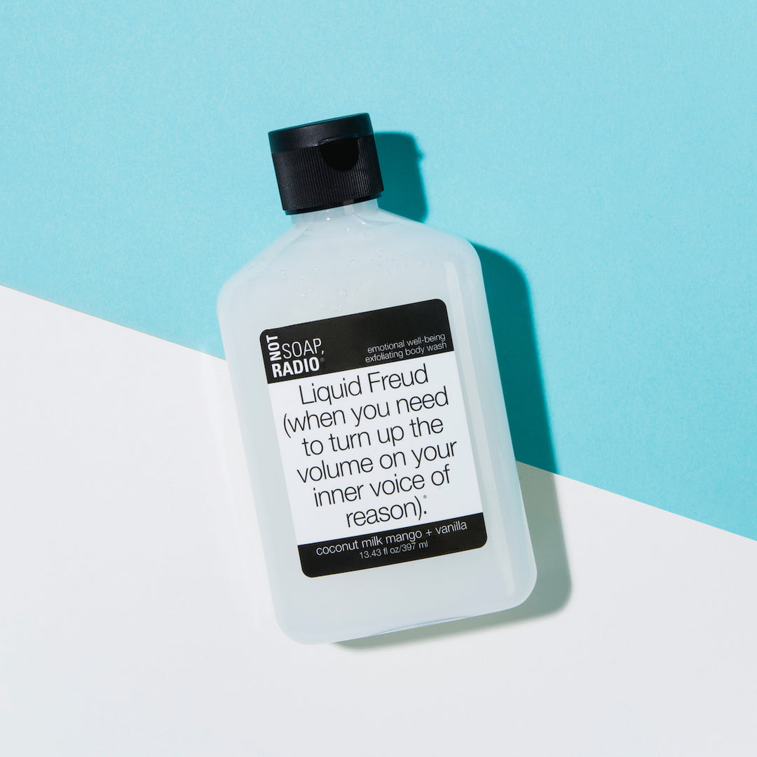 Coconut milk mango vanilla scented exfoliating body wash flatlay on a blue/white background