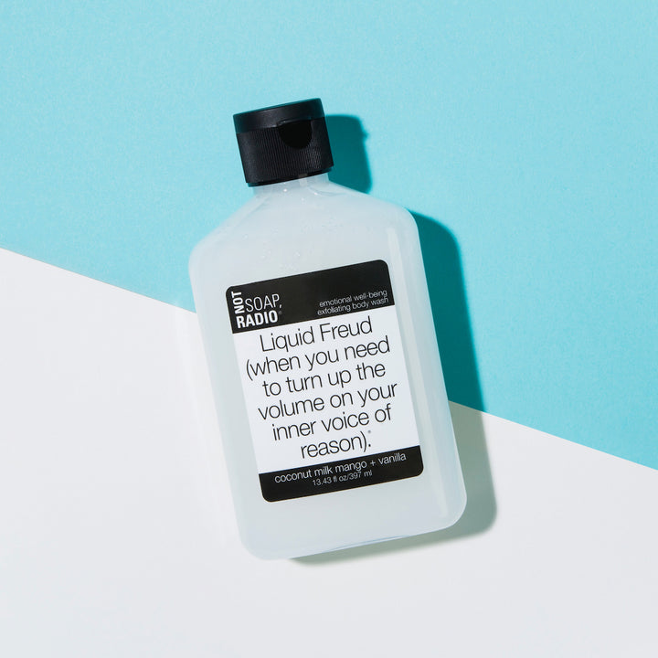 Coconut milk mango vanilla scented exfoliating body wash flatlay on a blue/white background