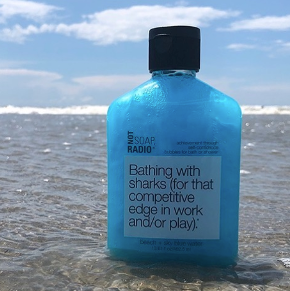 A beach and sky blue water scented bubble bath gel standing in the waves from a beach.