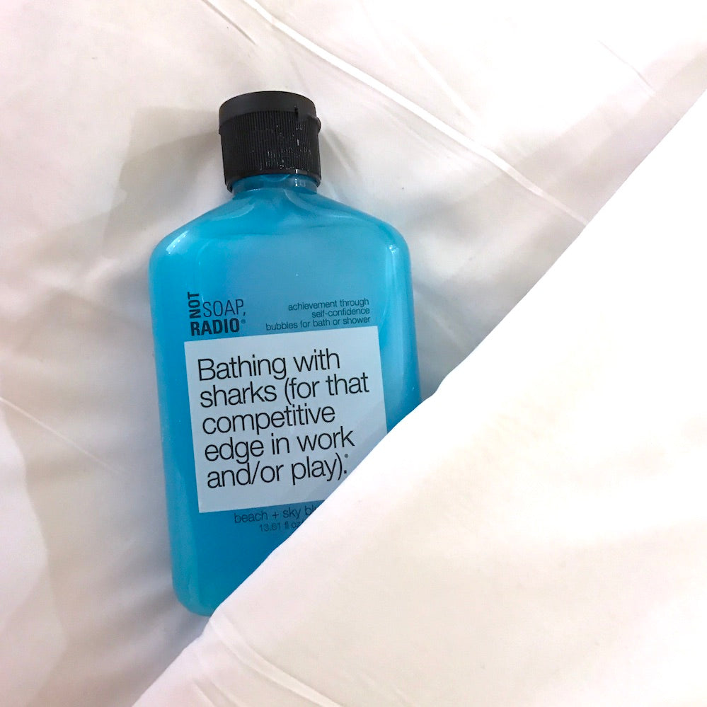A fresh clean scented shower gel being tucked into white linen sheets.