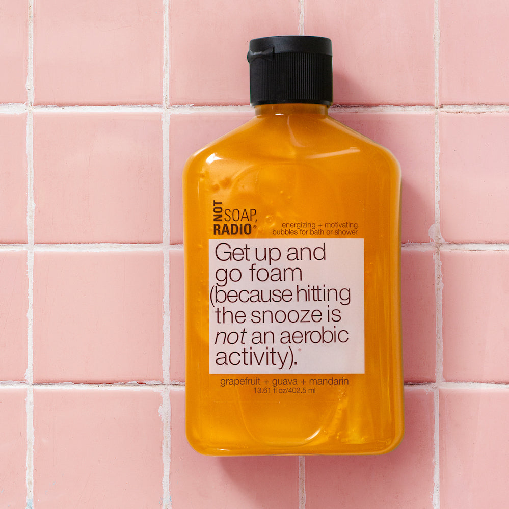 A citrus scented shower gel on a pink tile background.