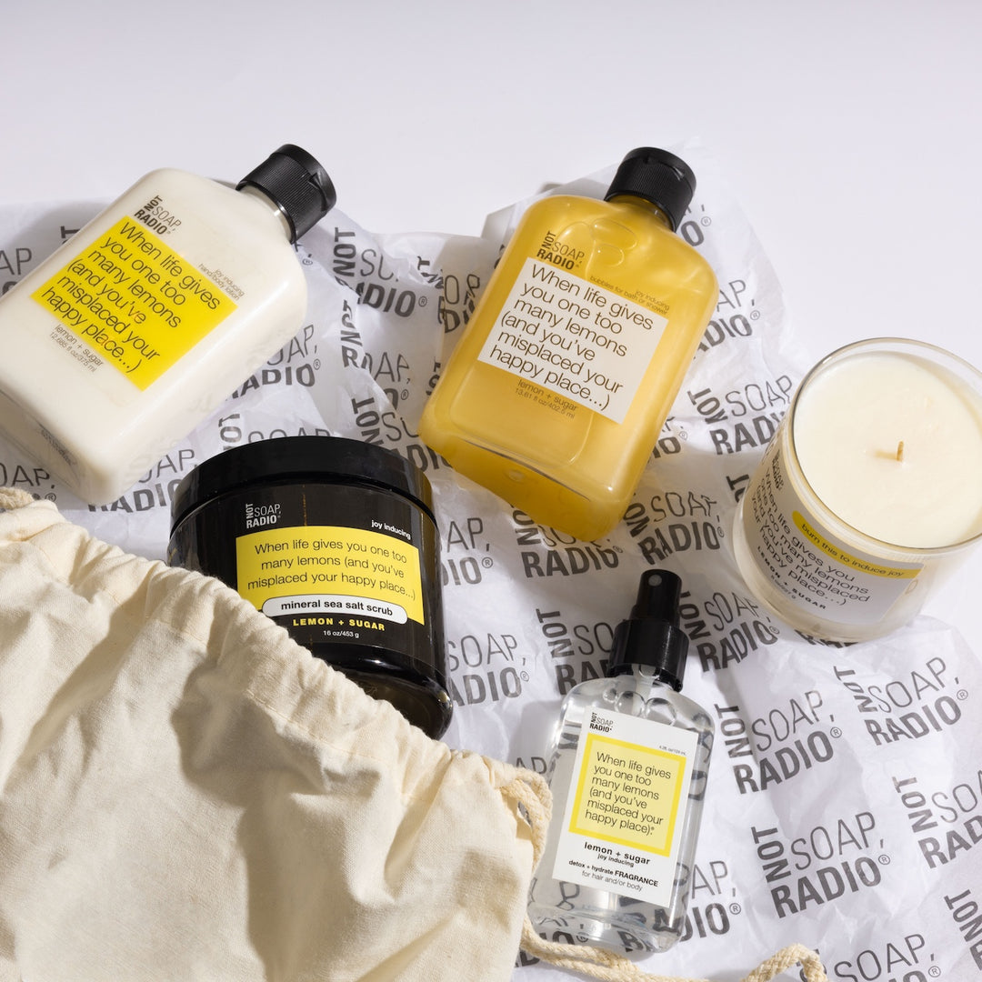 Women's lemon bath and body products spilling out of a drawstring gift bag.