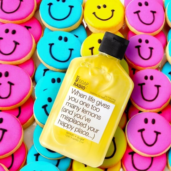Lemon sugar scented bubble bath flat laid on top of smiley face cookies
