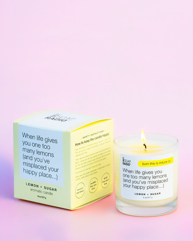 When life gives you one too many lemons (and you've misplaced your happy place...) lemon + sugar scented candle with box on a pink background.