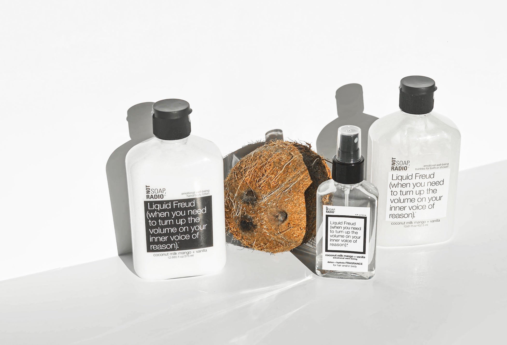 Liquid freud coconut milk mango + vanilla scented lotion, fragrance spray and bath.shower gel on a white background with a coconut