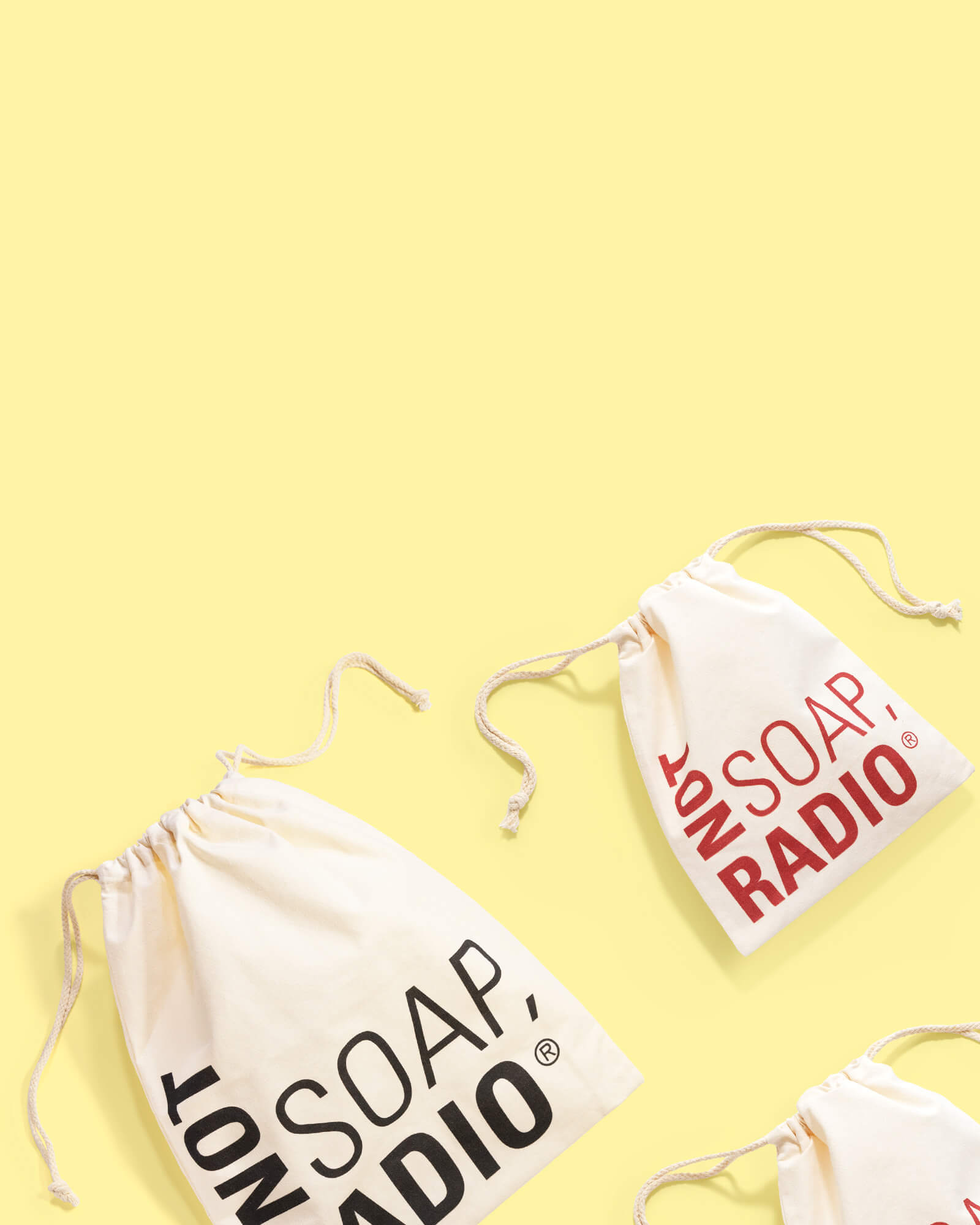 Canvas drawstring gift bags with the Not Soap, Radio logo on them, on a yellow background.