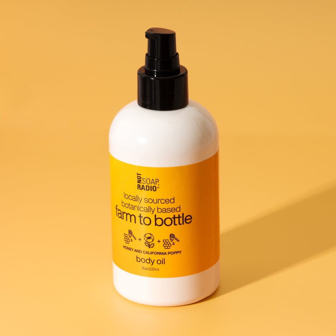 Honey and California Poppy scented body oil by Not Soap Radio — locally sourced, botanically based formula in amber-toned packaging, photographed on a warm yellow background.