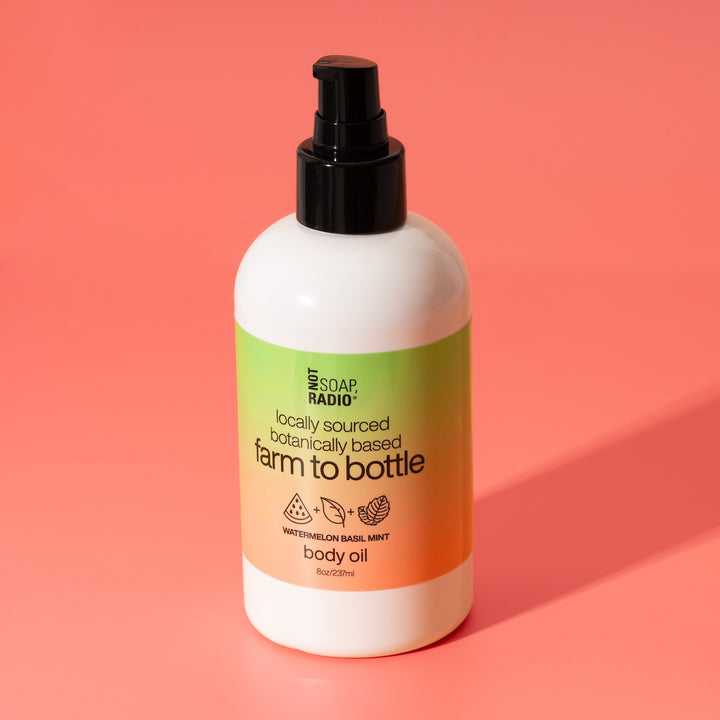 Watermelon Basil Mint scented body oil by Not Soap Radio — locally sourced, botanically based formula in green and pink packaging, photographed on a pink background.
