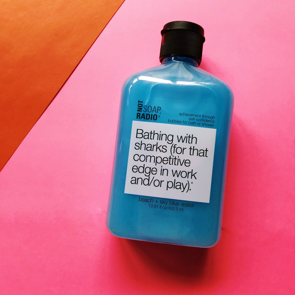 A confidence boosting bath or shower gel flatlay on top of a pink and orange background.