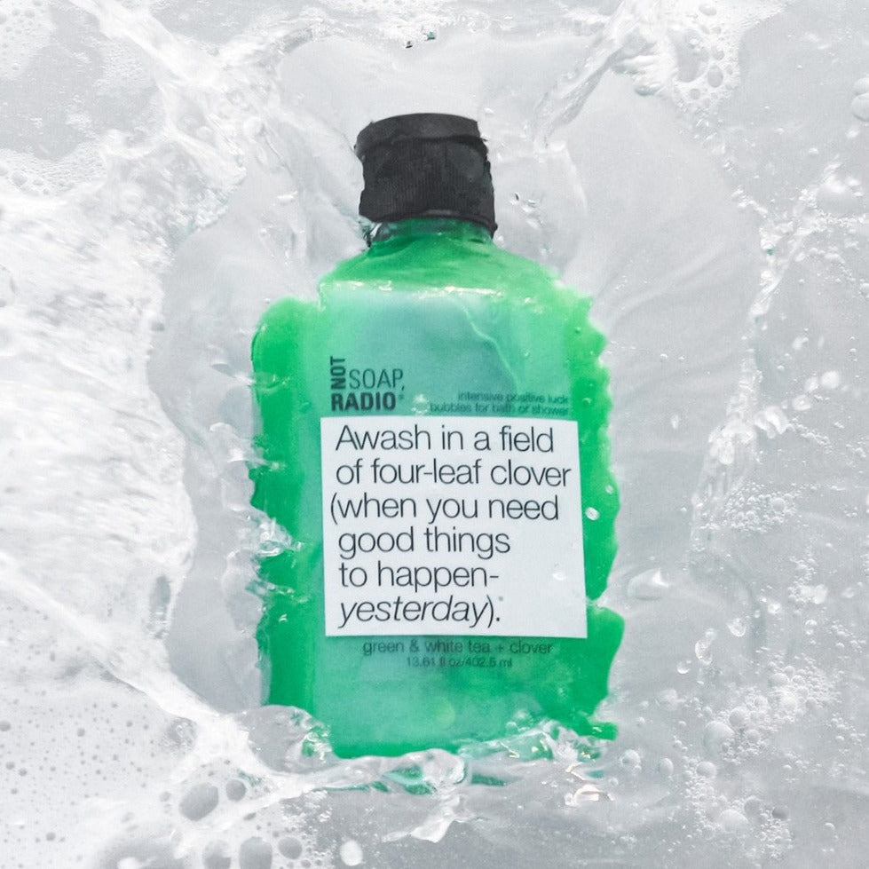 A four-leaf clover themed shower and bath gel splashing into water.