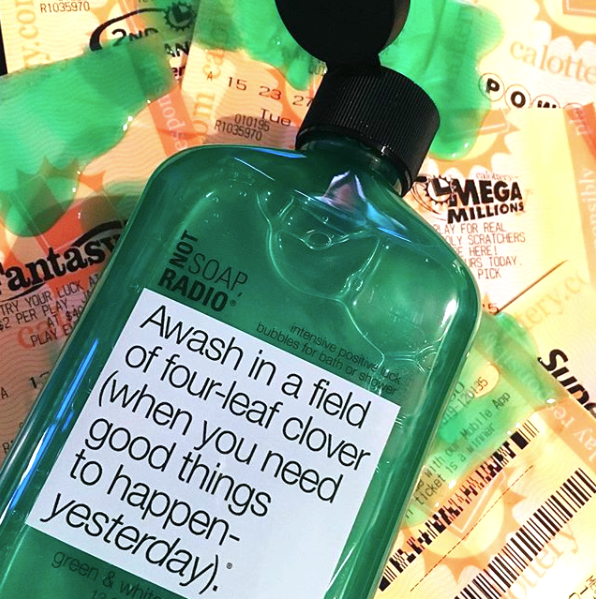 A good luck themed shower gel spilling on a pile of lottery tickets.
